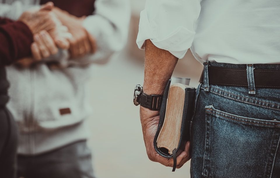 person in white long-sleeved shirt holding book